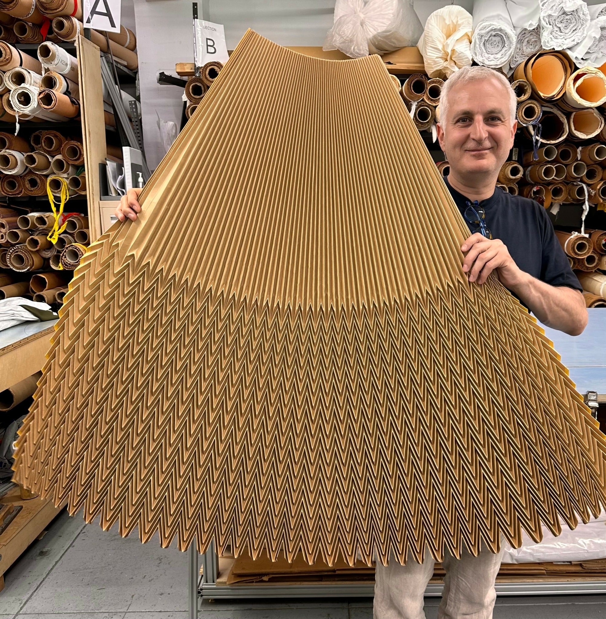 Man holding a large piece of corrugated cardboard in a pleating factory