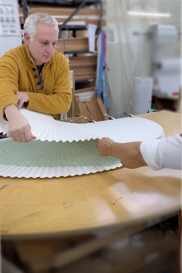 Two people working together to close a pleating mold on a sunburst table.