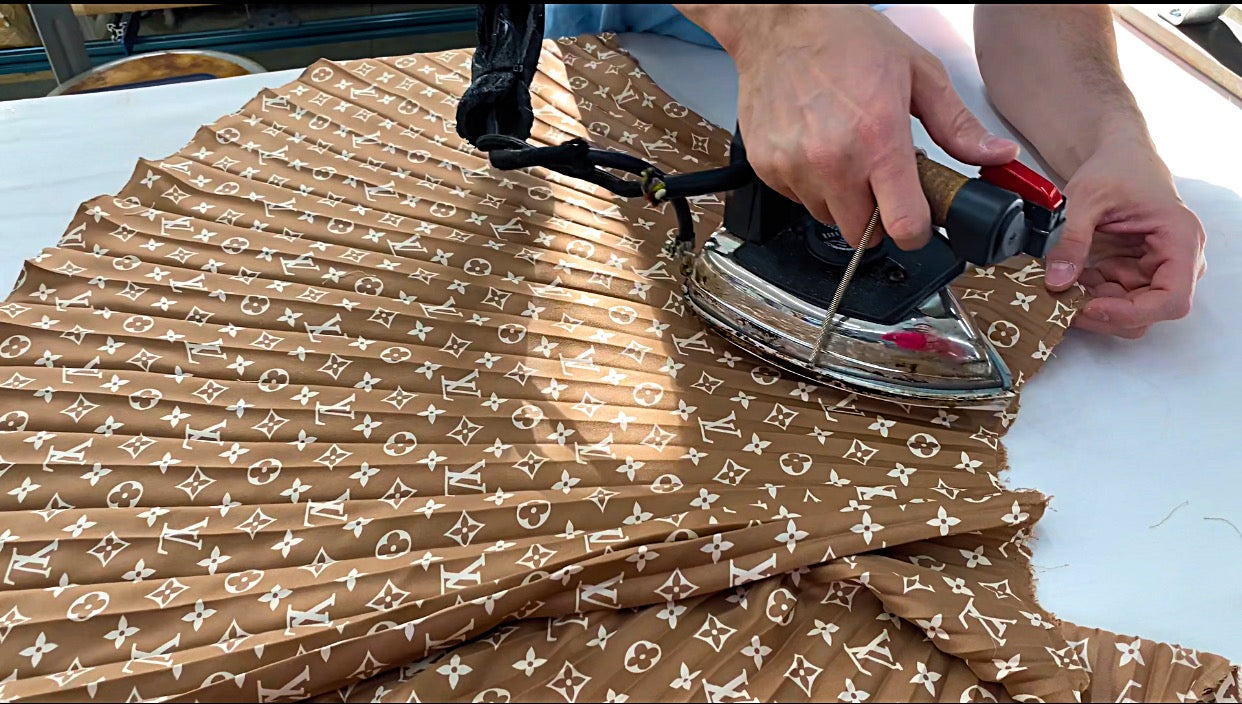 Pressing flat a sunburst accordion pleated Louis Vuitton monogram silk skirt for repleating.