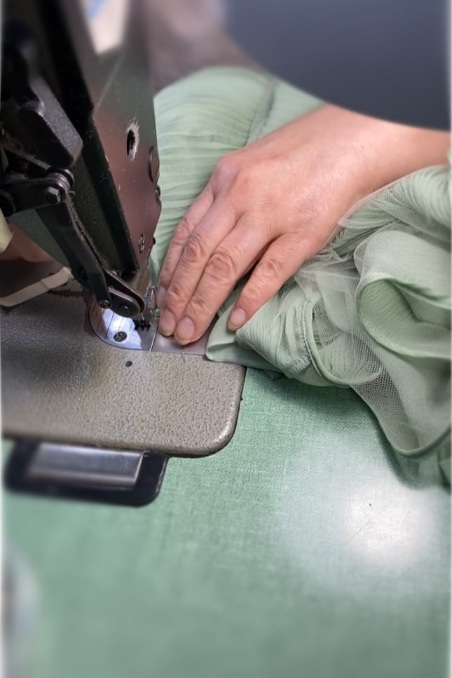 Person using a sewing machine on green silk chiffon fabric