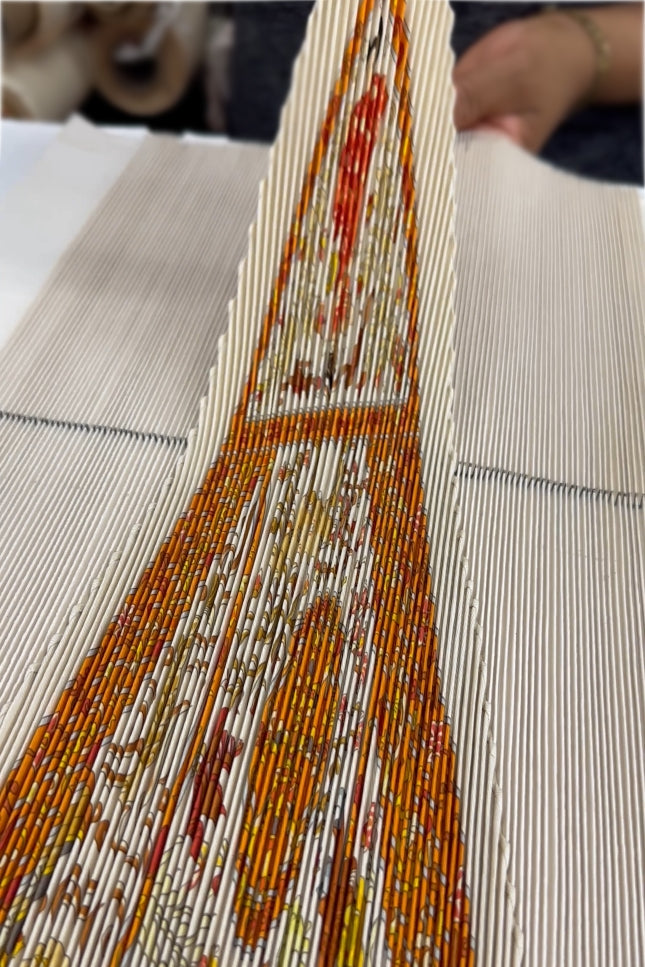 Close-up of a pleated Hermes Scarf with intricate patterns and colors coming out of a pleating mold