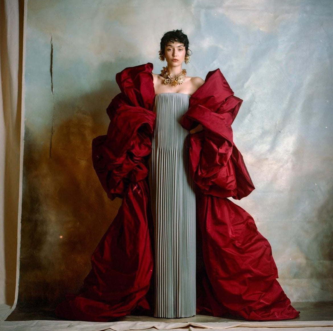 straight accordion merged pleated column dress with an oversized floor length red jacket  