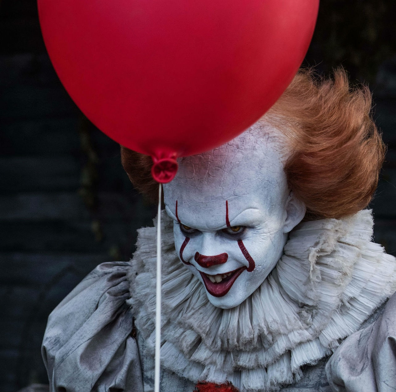 Pennywise holding a red ballon with a pleated collar and puff sleeves