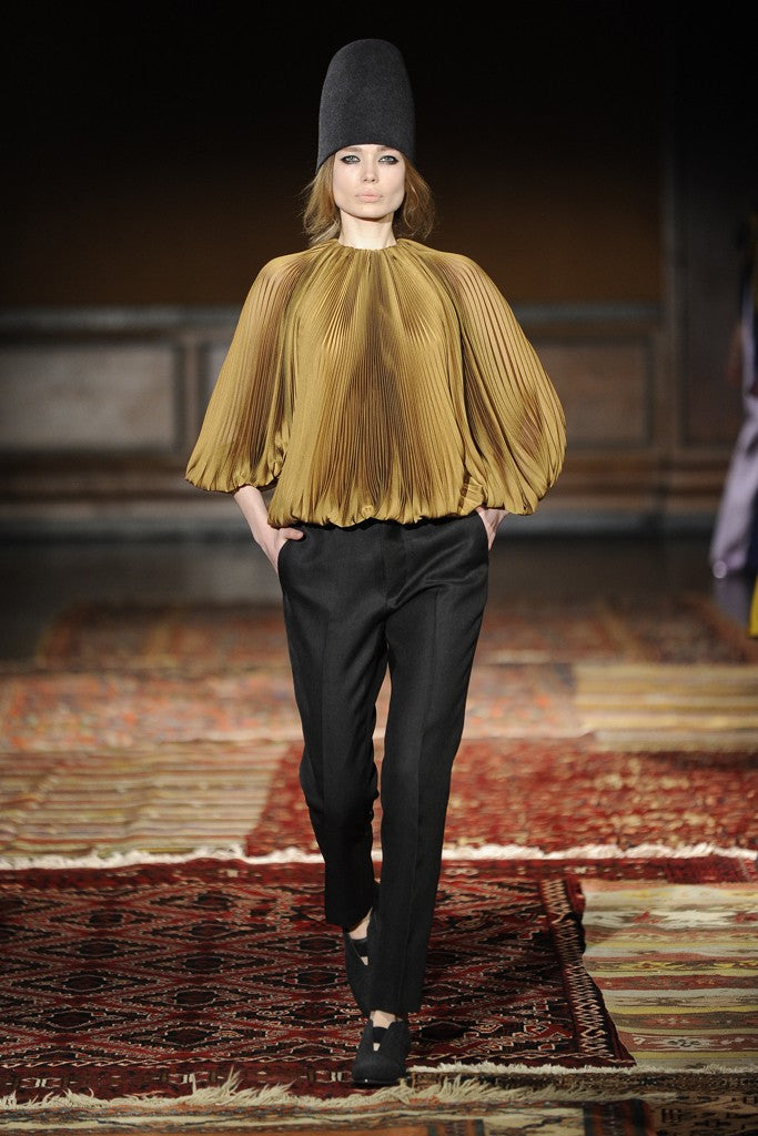 Model wearing an accordion pleated shirt with black pants